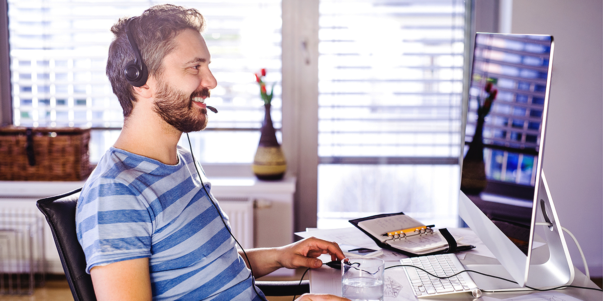 Man sitting in front of a computer screen with headphones on and plugged in