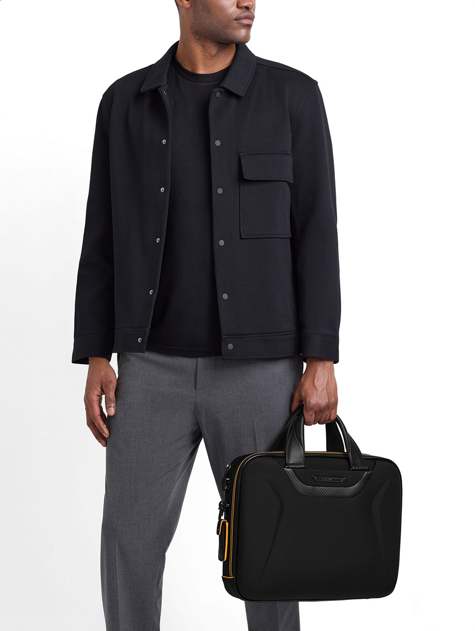 Model holding TUMI McLaren Axle Slim Brief by top handle