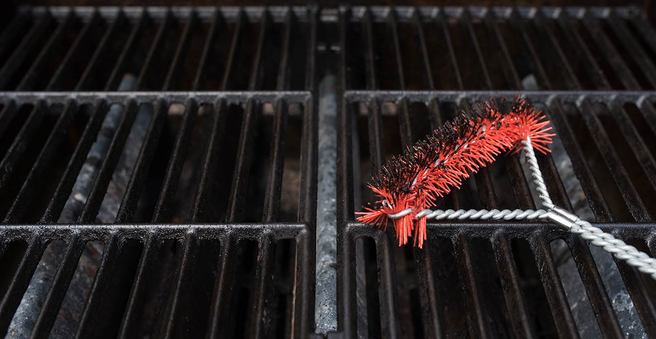Cleanign brush over a gas grill surface