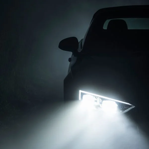 An image of a car in darkness with bright headlights