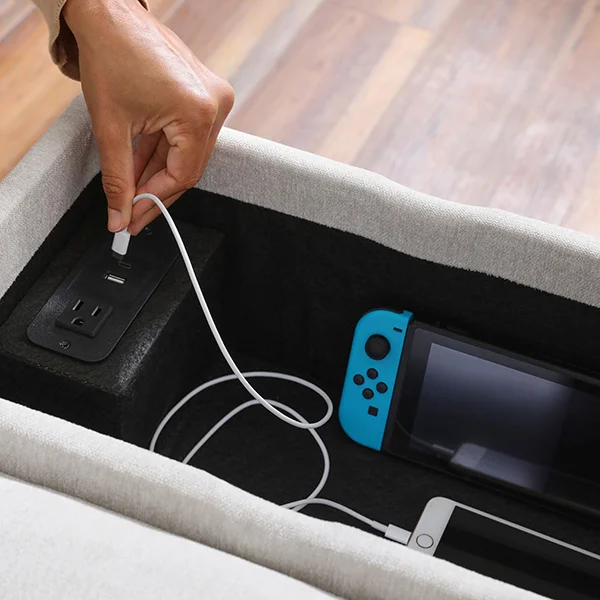 A close up of an open sectional console with a phone and gaming console sitting inside of it