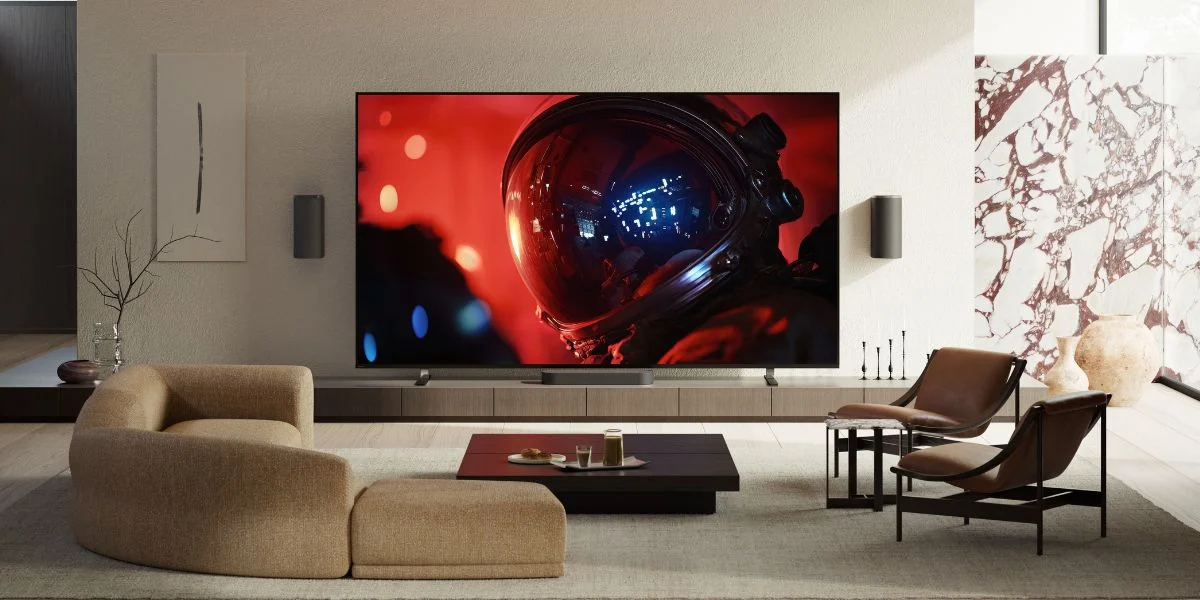 A large Sony TV with an astronaut on-screen sits on a low TV console in front of a tan sectional.