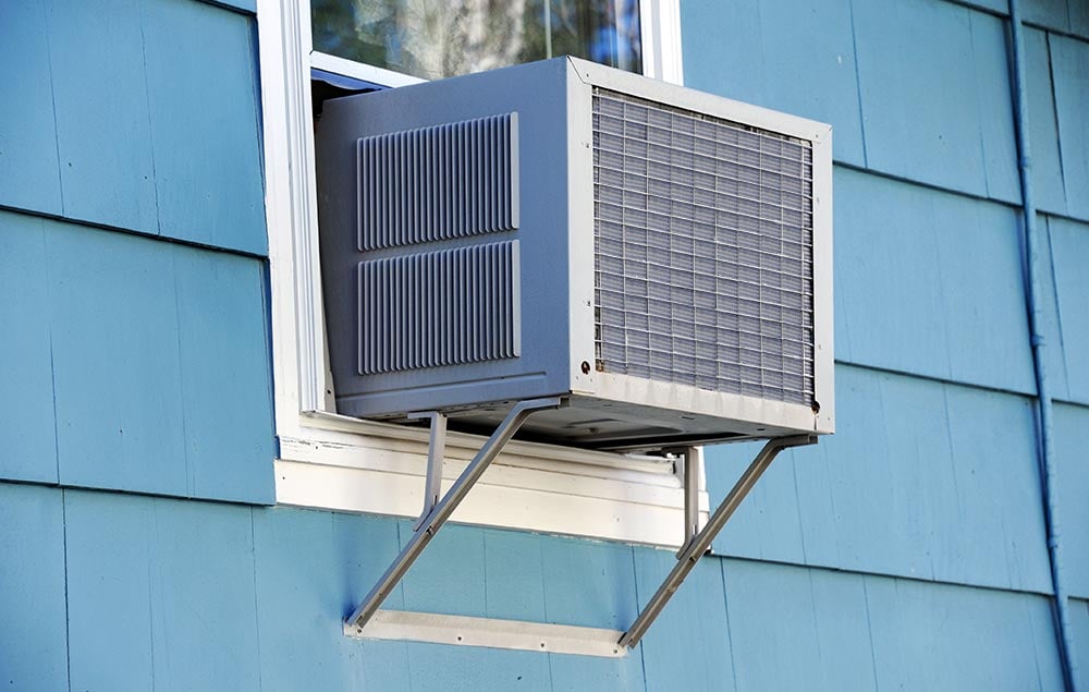Window air conditioner on the side of a blue house