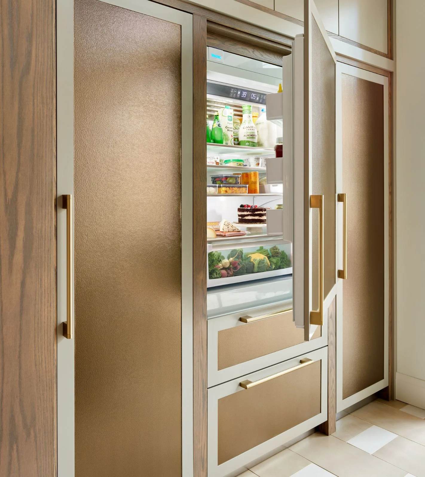 A modern kitchen fitted with a built in panel ready viking refrigerator showcasing the door slightly ajar showing what's inside