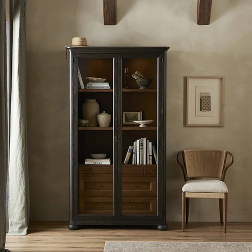 A cozy room featuring a chair beside a tall bookcase filled with books