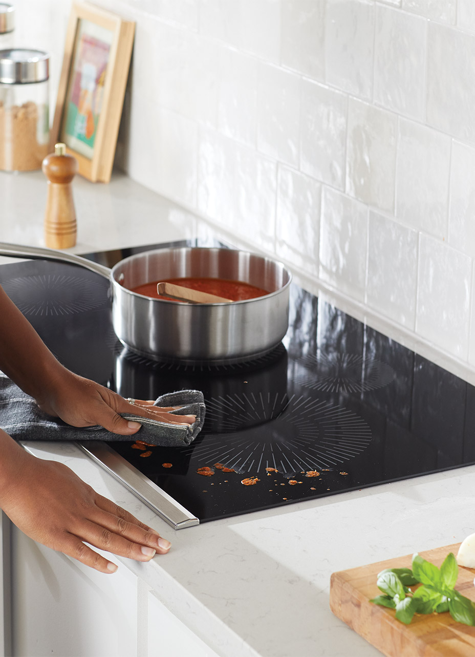 a person cleaning up a sauce spill on the gallery induction cooktop