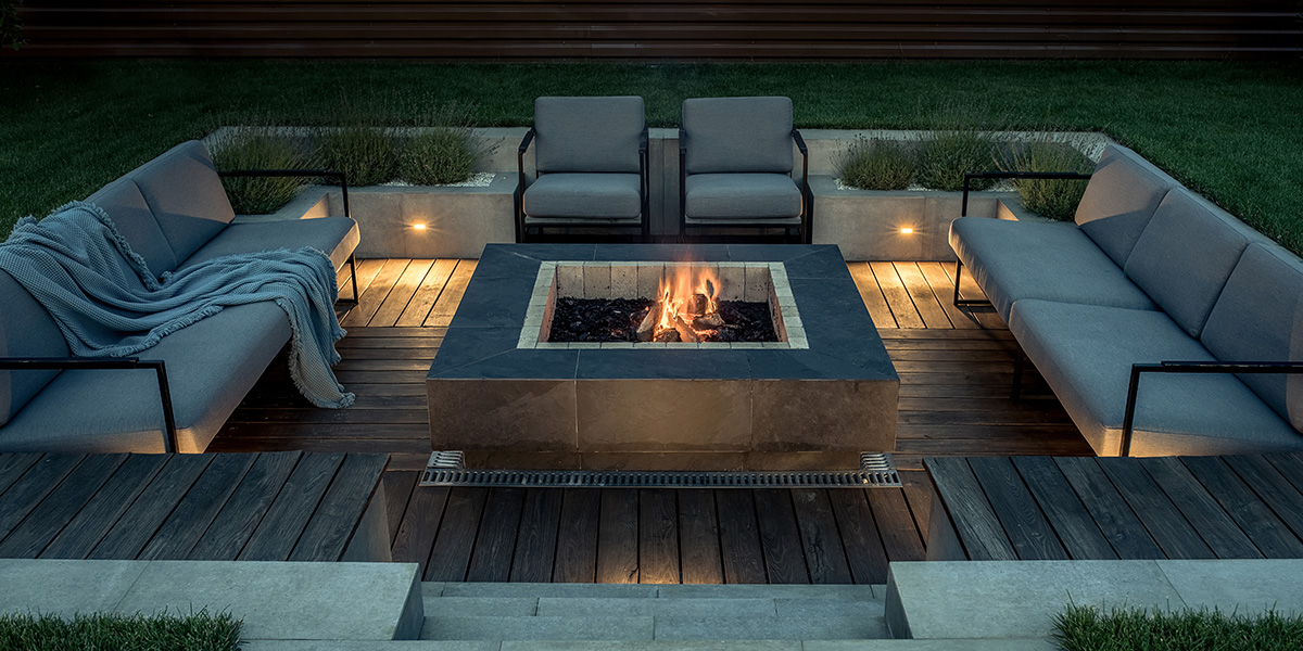 Square fire pit surrounded by outdoor love seats and arm chairs