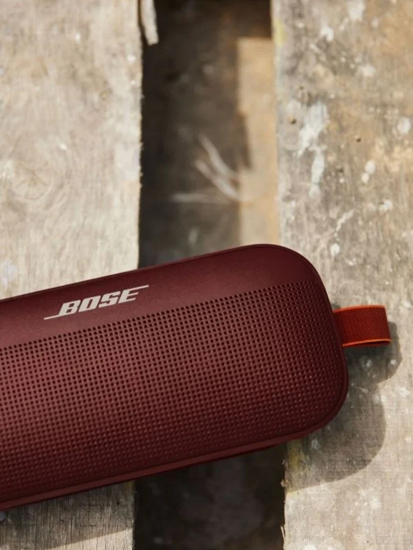 Close up on a maroon Bose portable speaker on a wooden dock