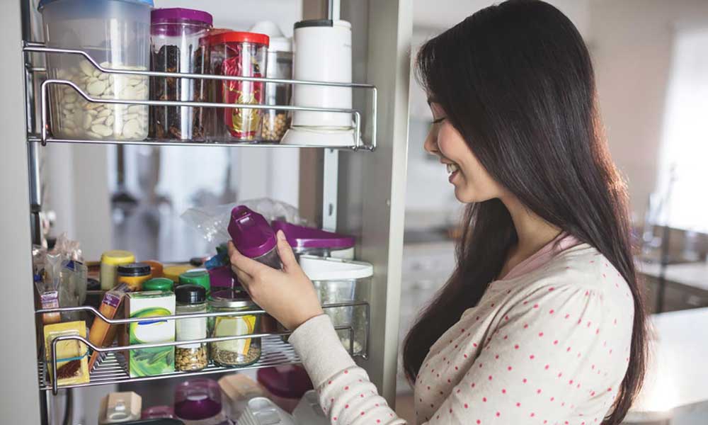Person organizing food in kitchen cabinet