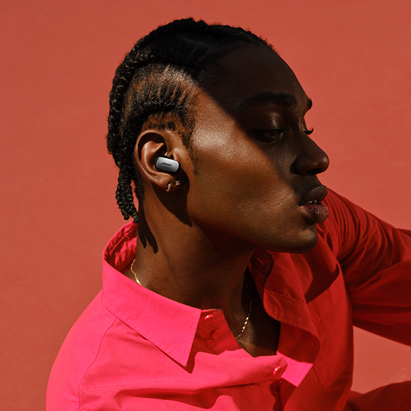 A man sitting in the sun with a black earbud in his ear