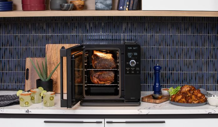 Ge profile indoor smoker on the counter with the door ajar shocasing the meat inside