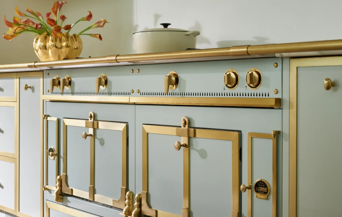 La Cornue Château range detail with gold hardware and cast iron cookware