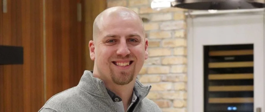 Rafal Kubalski in a gray quarter zip, smiling, in one of Abt's inspirational kitchens