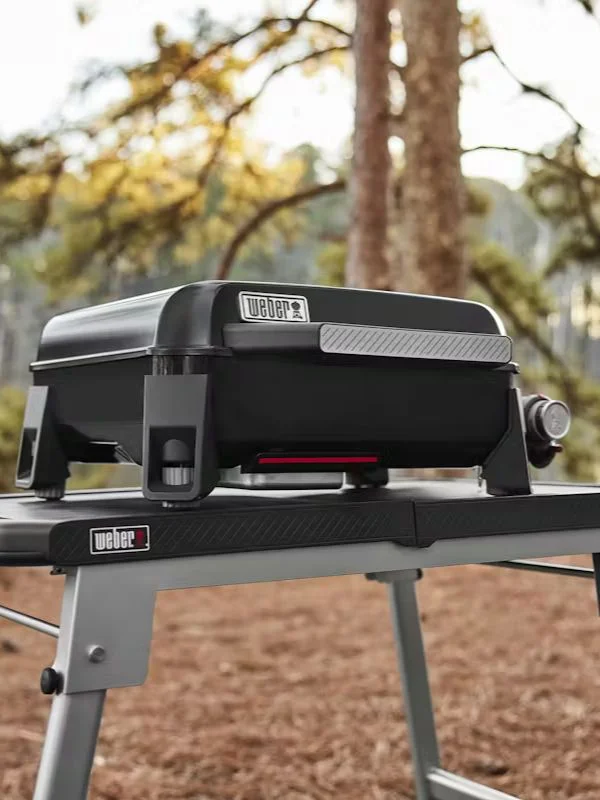 A tight shot on a weber portable grill siting on top of a weber portable table