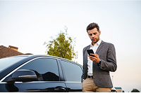 Man controlling smart security system from mobile app near car