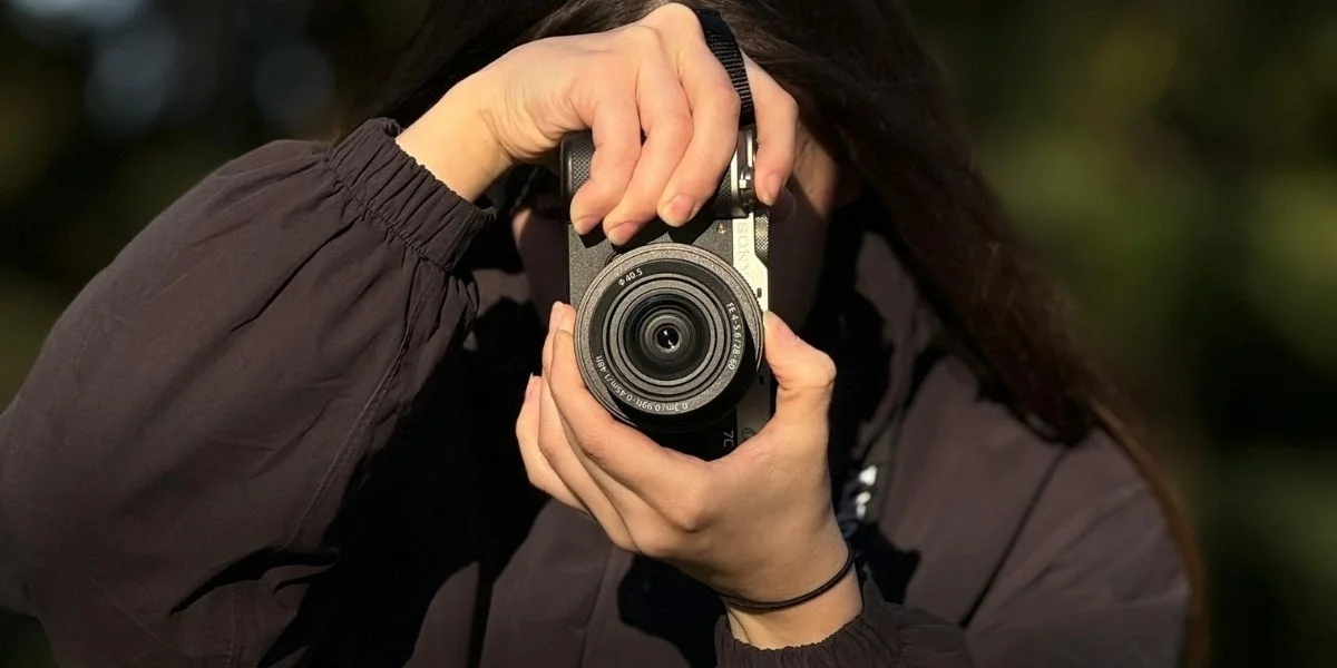 A woman shooting with a DSLR camera outside.