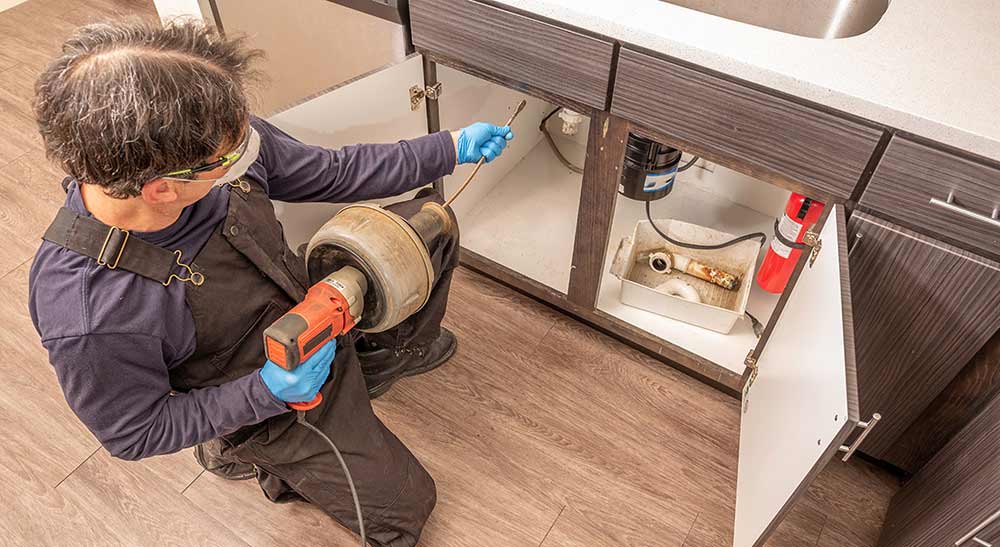 Plumber Using an Auger to Unclog a Sink Drain