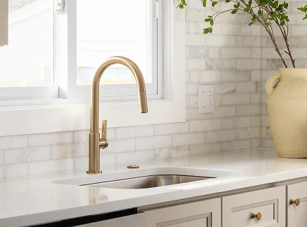 A plumber servicing a pipe under a sink