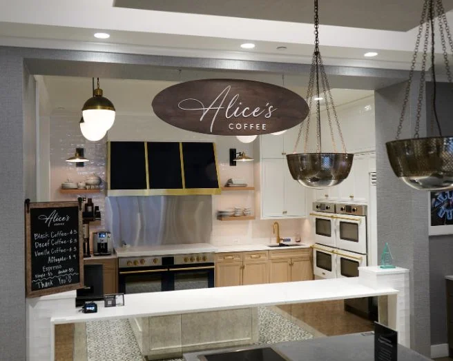 Photo of Alice's Coffee with a white serving counter and BlueStar appliances with brass hardware.