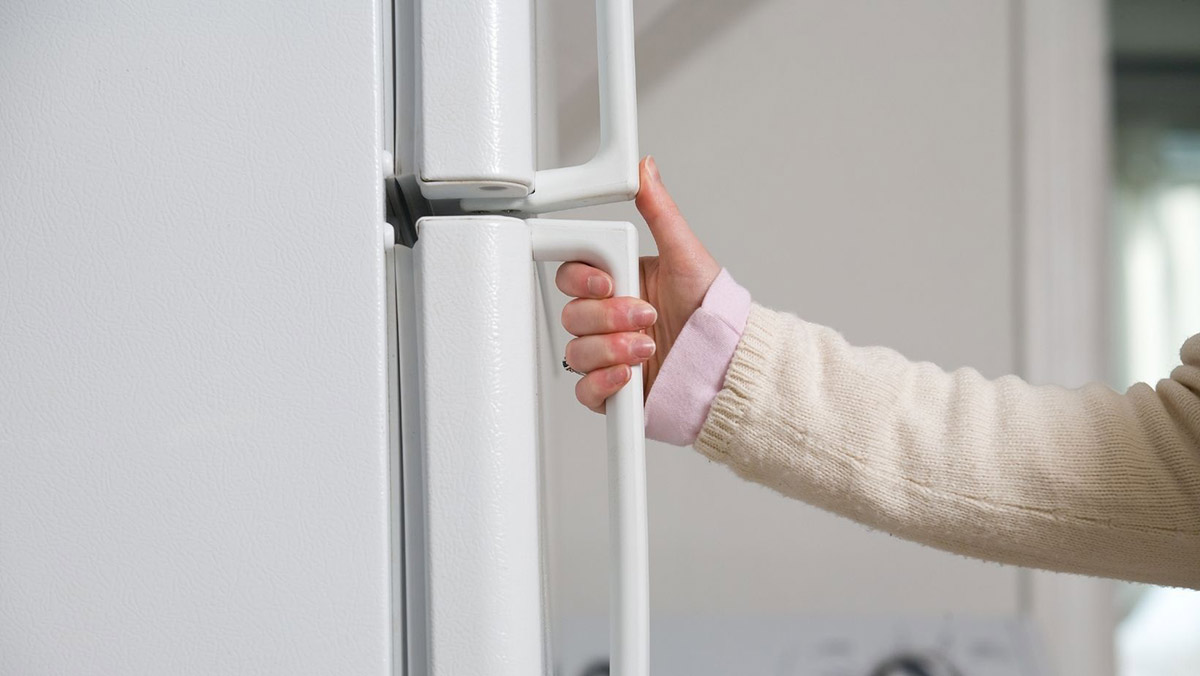 Person grabbing door handle of a refrigerator
