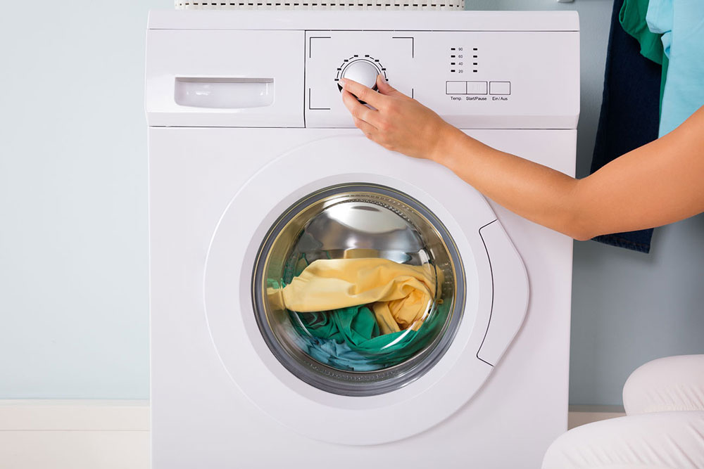 Person adjusting controls of a washer dryer combo