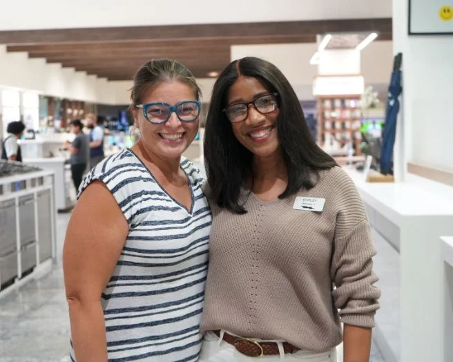 Two Abt employees with their arms around each other on the Abt sales floor.