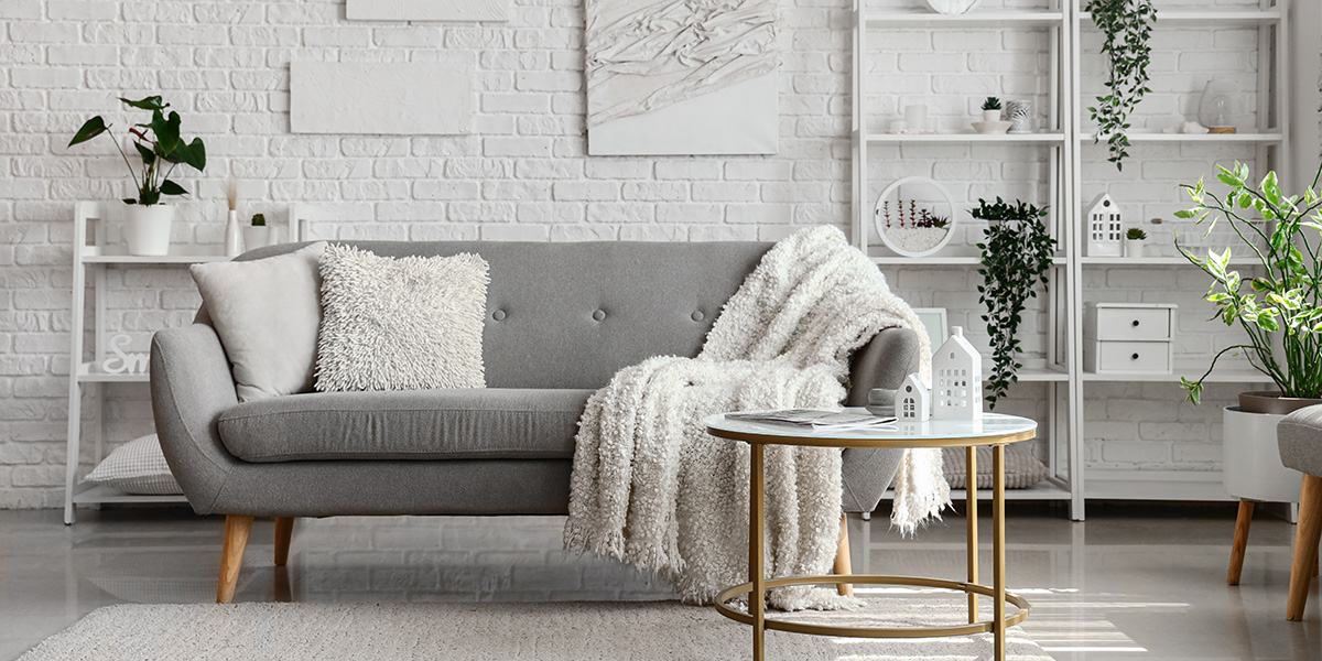 A small white living room with a grey sofa, a coffee table and ladder bookshelves