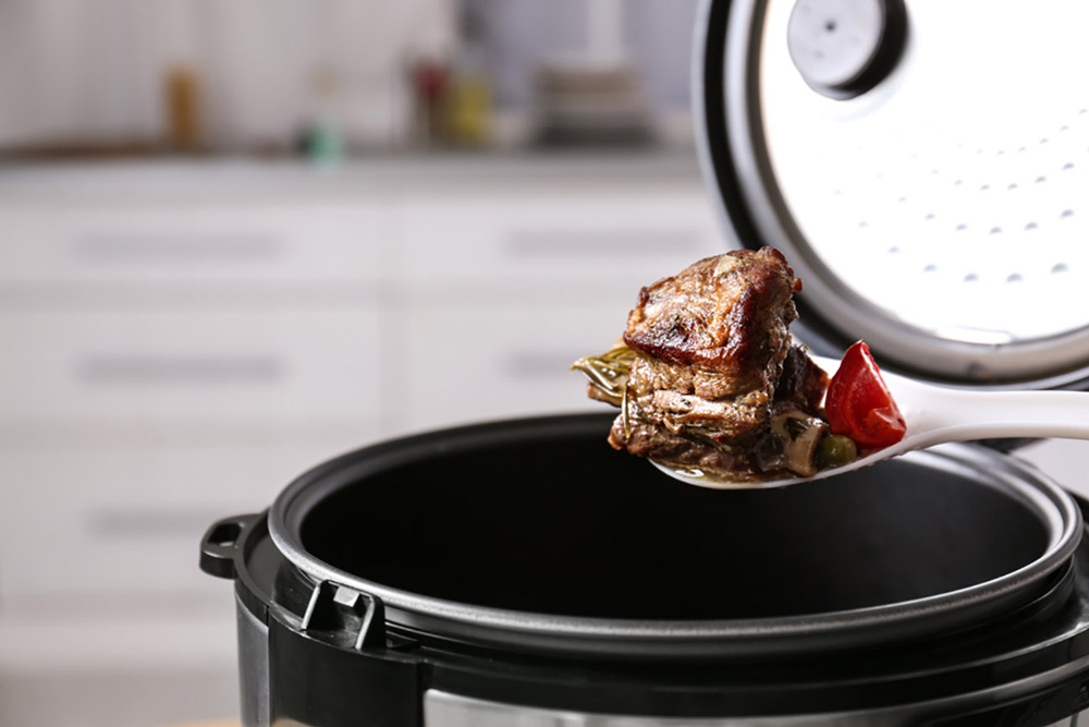Food on spoon above pressure cooker