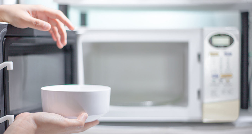 Person using microwave to reheat leftovers