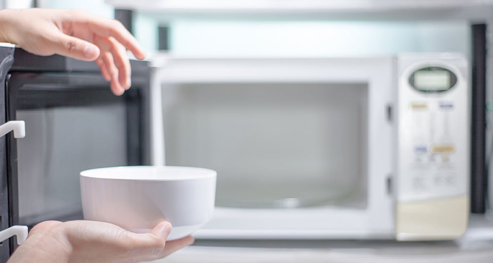 Person using microwave to reheat leftovers