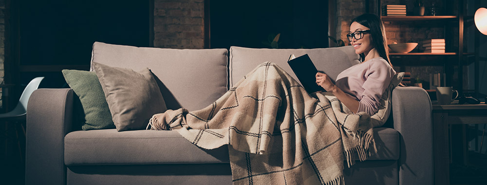 Person reading under a blanket