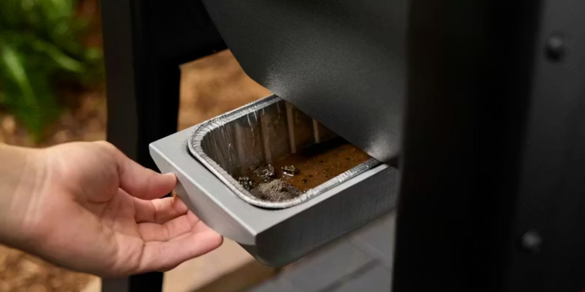 Person replacing the drip tray on their pellet grill.