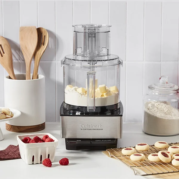 The Cuisinart Custom 14 Cup food processor sitting on a countertop next to fruit and cookies while butter and flour sit in the bowl