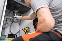 Person fixing pipes under a sink
