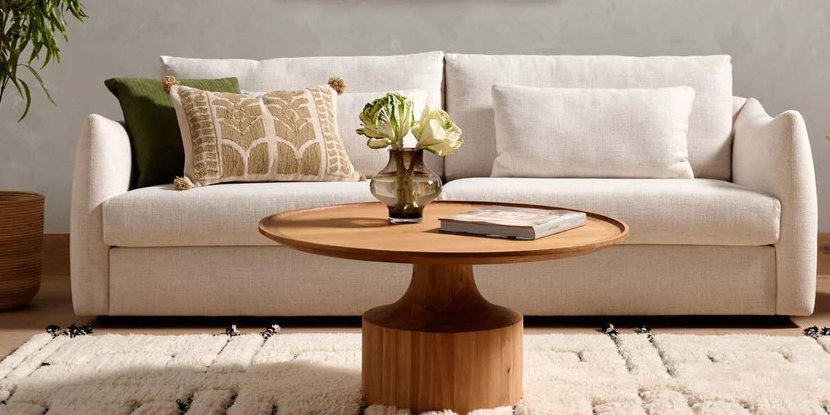 cream linen sofa with round wood coffee table in front of it