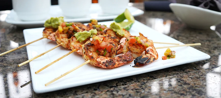 Shrimp skewers on a plate with various toppings