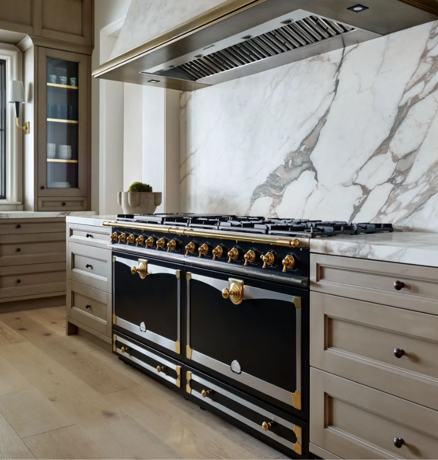 Black La Cornue range in a wood-paneled kitchen with a dark stone island and pendant lighting