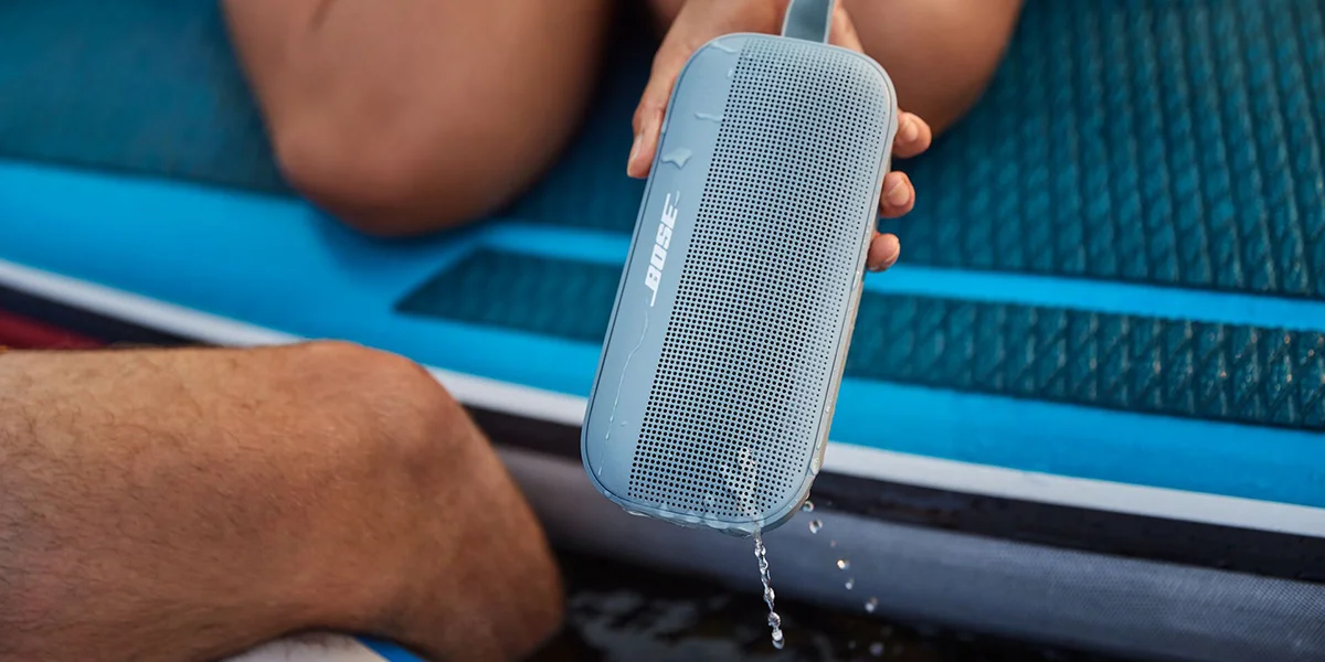 A zoomed in shot of a Bose soundlink speaker in someones hand on a paddleboard