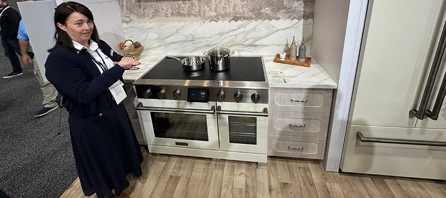 brunette woman giving demonstration of cream-colored induction range