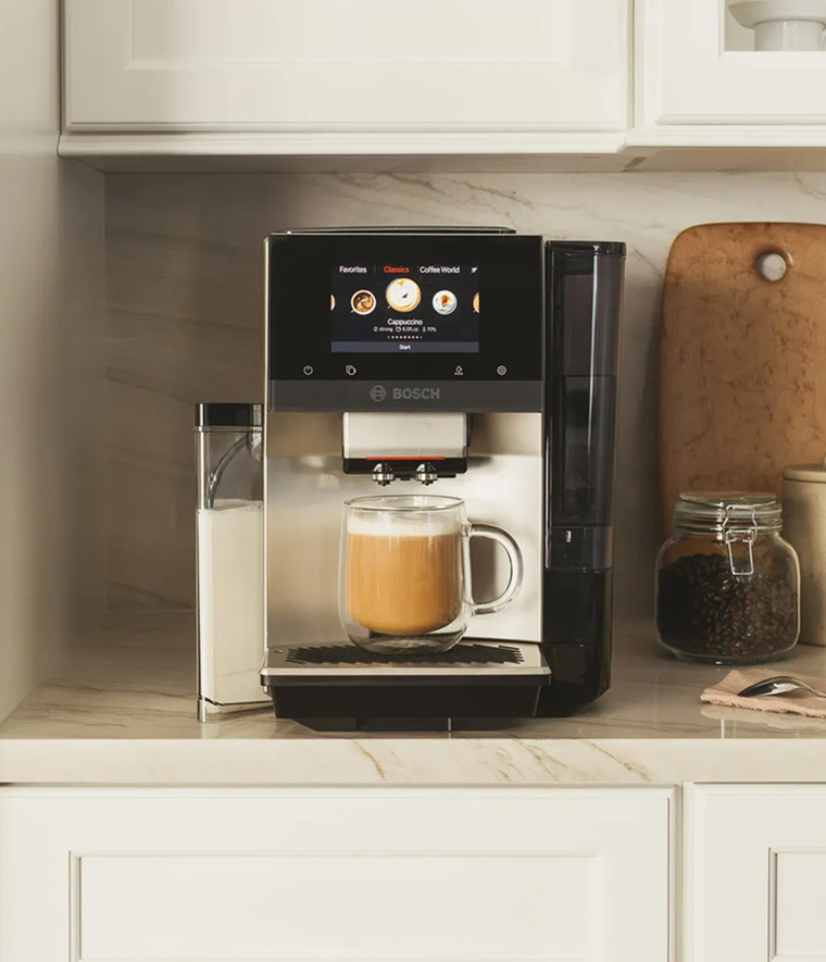 An Vitamix Ascent Blender atop a cement countertop with various fruits in the blender container