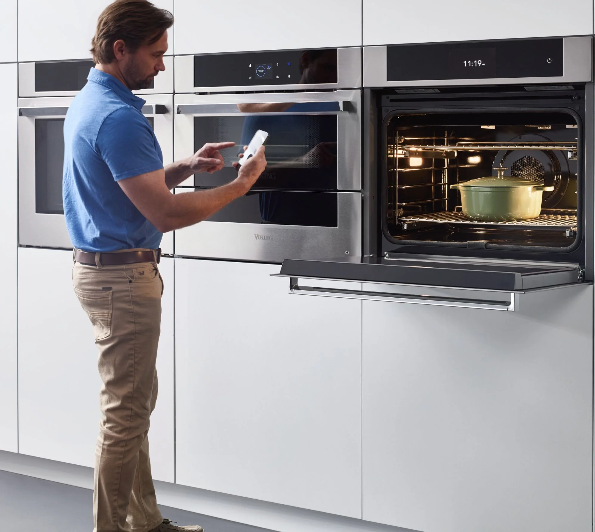 A man uses his phone and app to control and set temperatures on the viking rvl wall oven