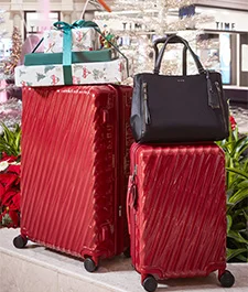 Tumi Luggage and tote bag plaed together with gifts atop one of the tumi luggage