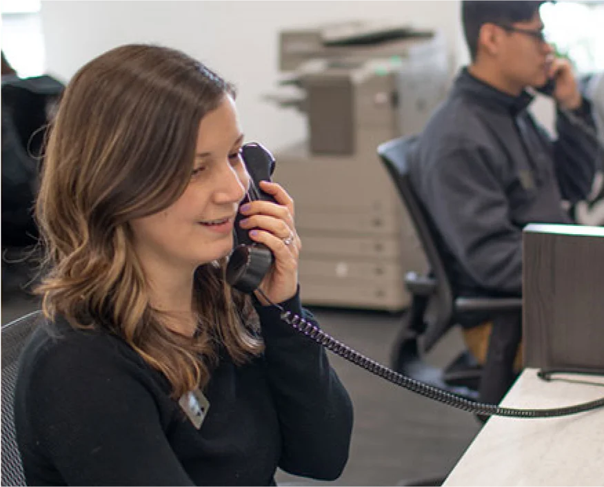 A retail customer service representative speaking on the phone in an office, assisting a customer with their inquiries