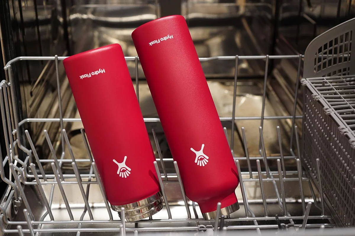 Two red Hydro Flask insulated tumblers inside the top rack of a dishwasher