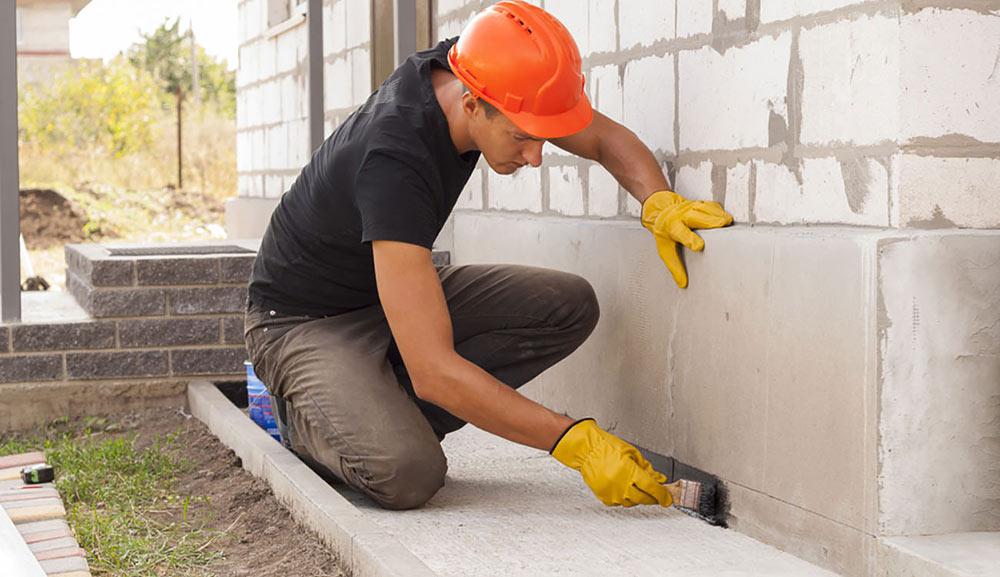 Man Pactching Exterior of Building in Preperation for a Flood