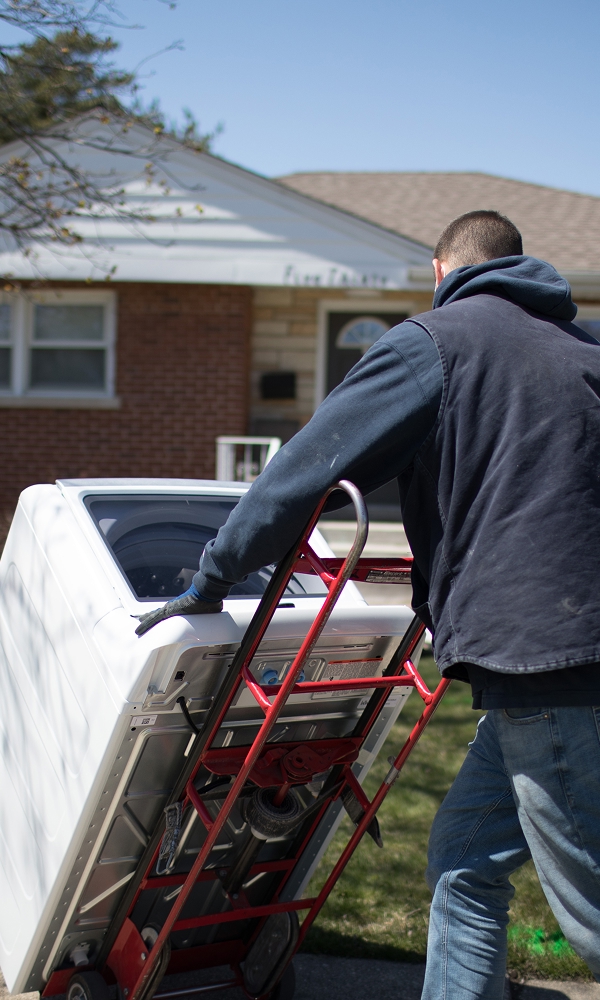 Technician transporting a washing machine for repair