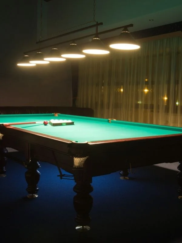 Dimly lit game room with a pool table and mood lighting as the main image focus