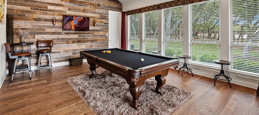 A pool table sitting on a rug in the middle of a hardwood room
