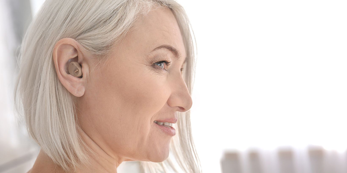 A bright white haired woman with an internal hearing aid