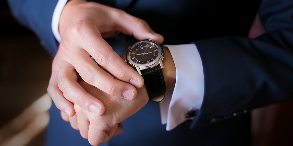 person in a dark suit putting on a watch
